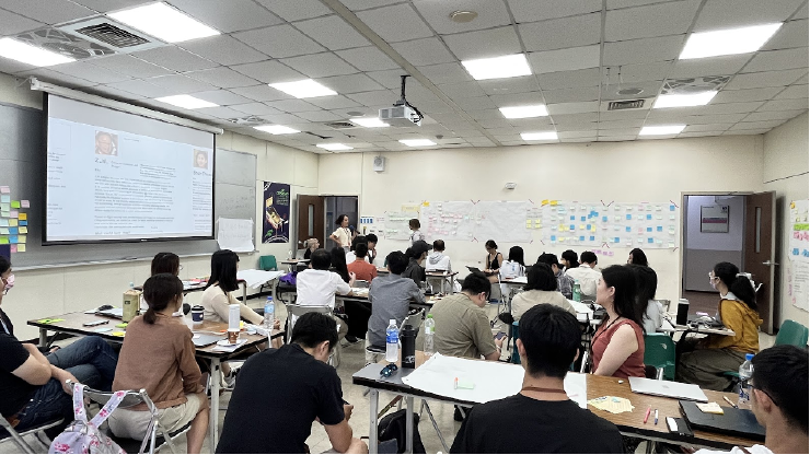 An image of the room during the workshop. People are sitting in seats as they listen while others present their journey maps.