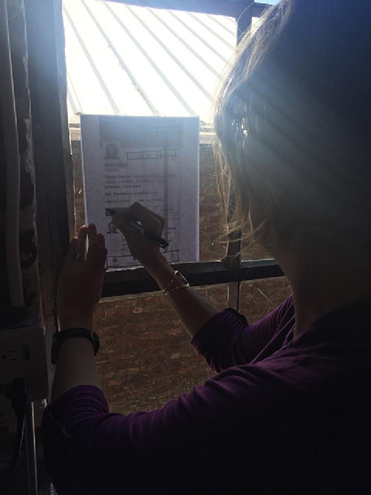 Image of the author working with screenshots held up against a window.