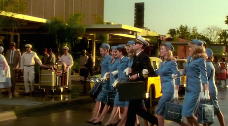 Still image from the movie Catch Me If You Can, picturing Leonardo DiCaprio dressed as an airline pilot surrounded by eight young women dressed as stewardesses.