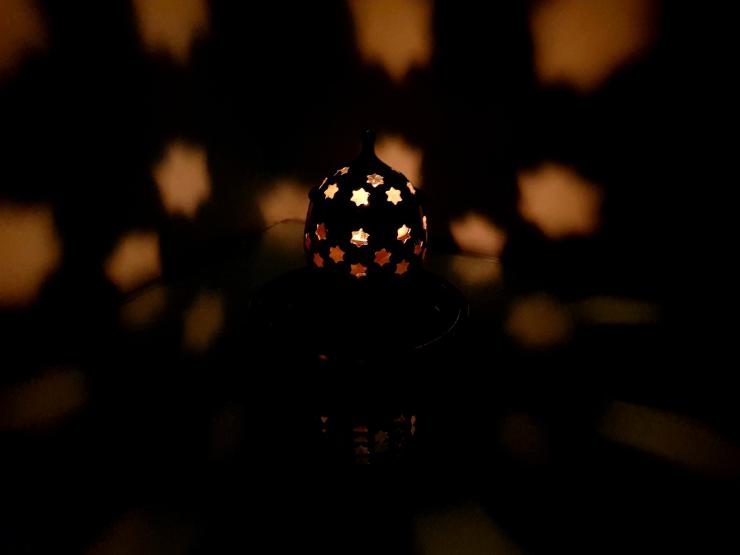 A photo of a lit candle with stars in the dark.